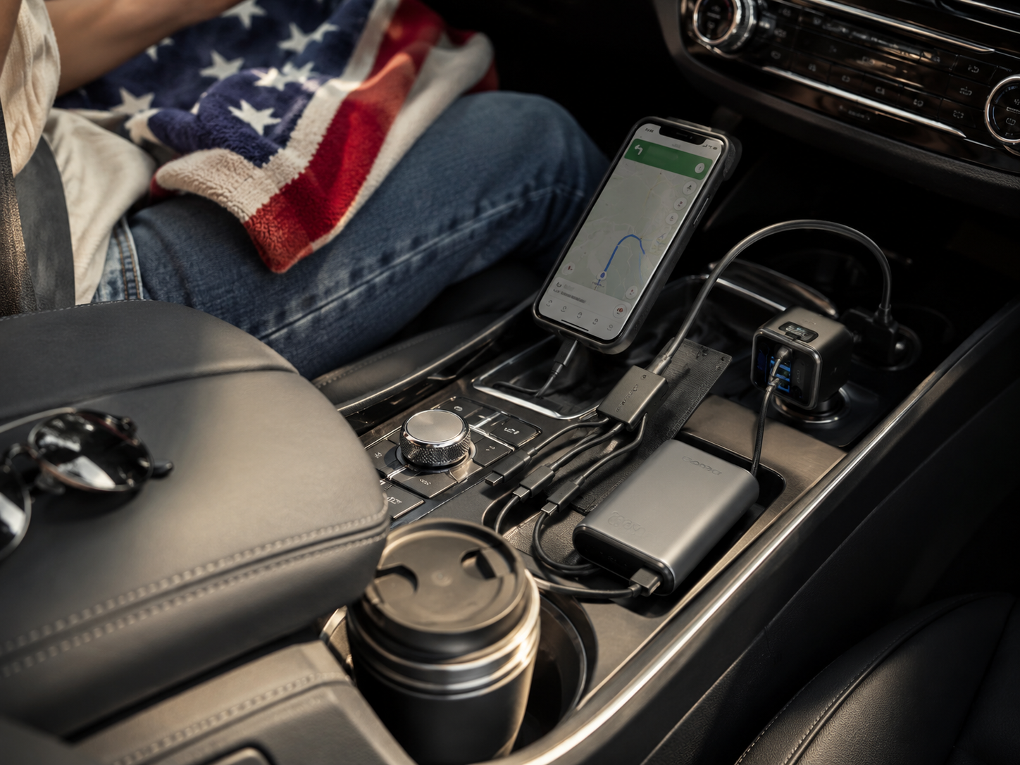 Road trip charging setup with phone navigation, power bank, multi-cable, and compact charger in a car console.