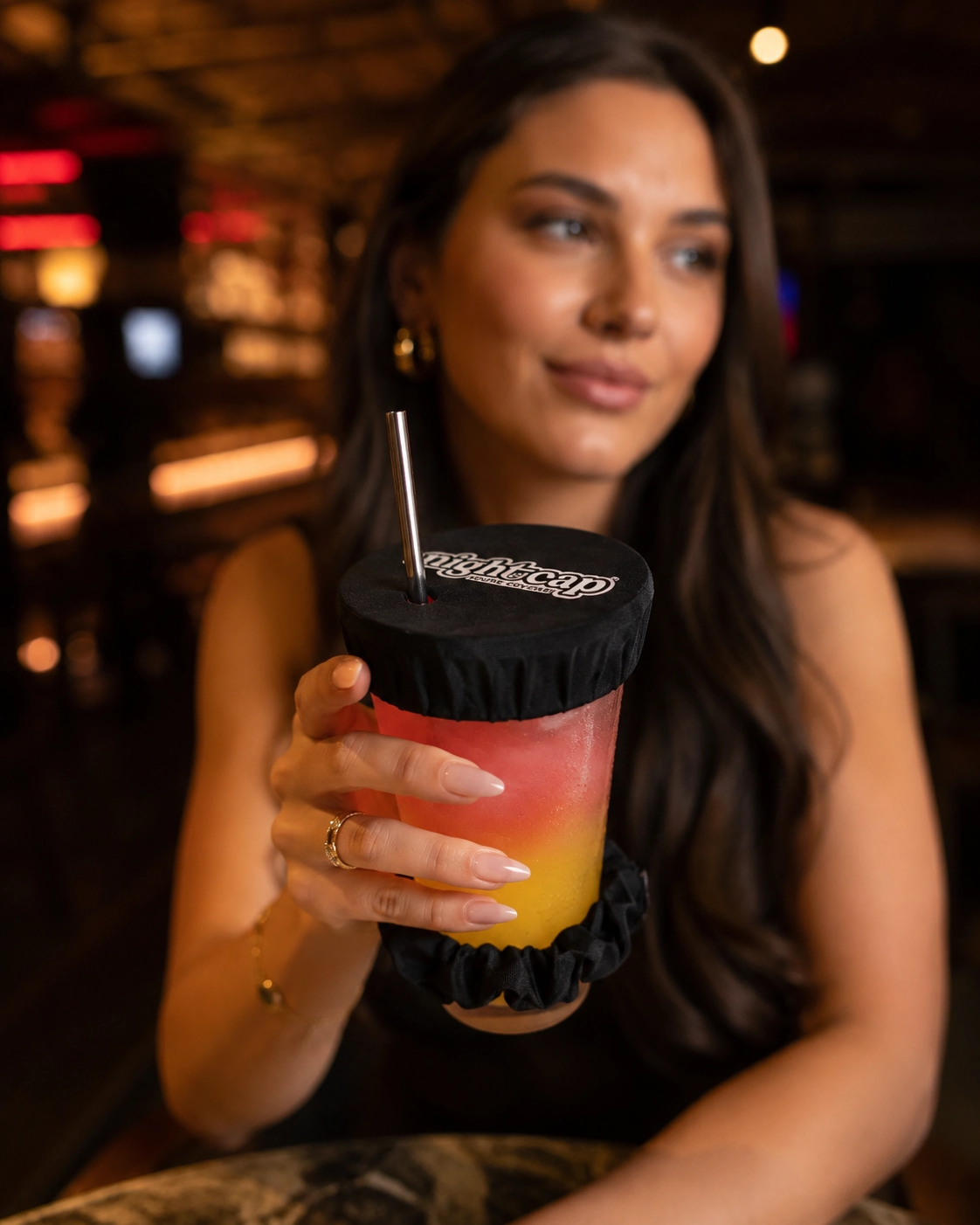 NightCap-style drink cover on a colorful drink at a bar for a safer night out.