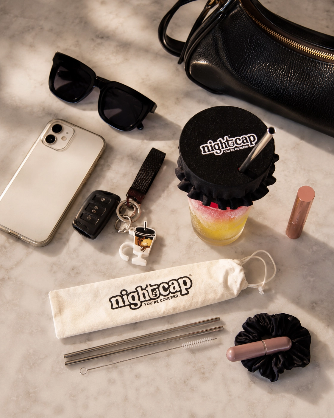 NightCap-style drink cover, scrunchie, straw set, phone, sunglasses, and going-out essentials.