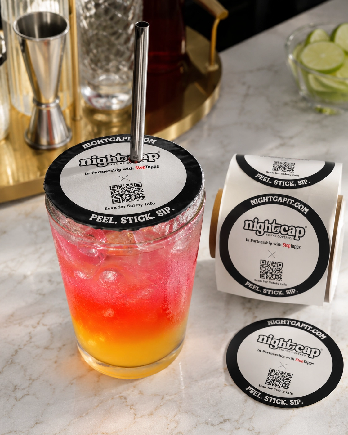 NightCap-style peel-and-stick drink cover on a cocktail with a straw at a bar.