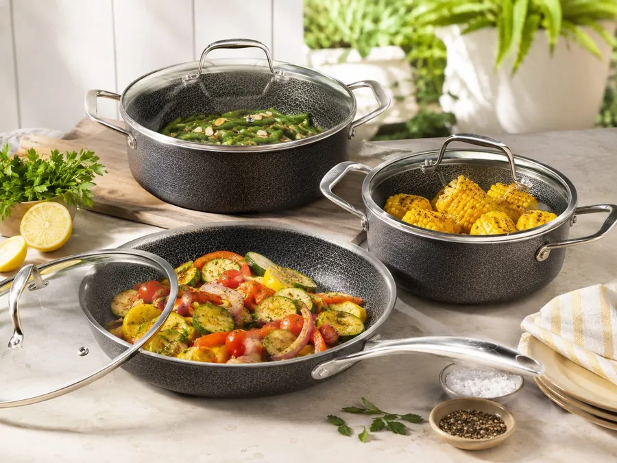 Backyard summer cookout setup with grill, cookware, serving dishes, and outdoor table essentials
