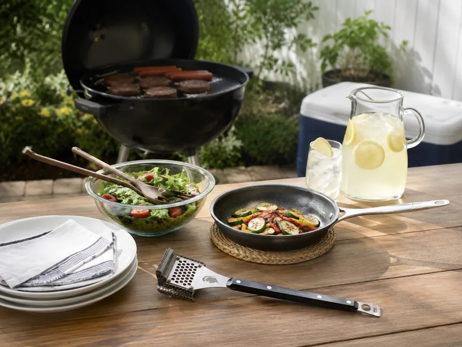 Livwell-style hybrid cookware with summer vegetables and side dishes prepared for a backyard meal